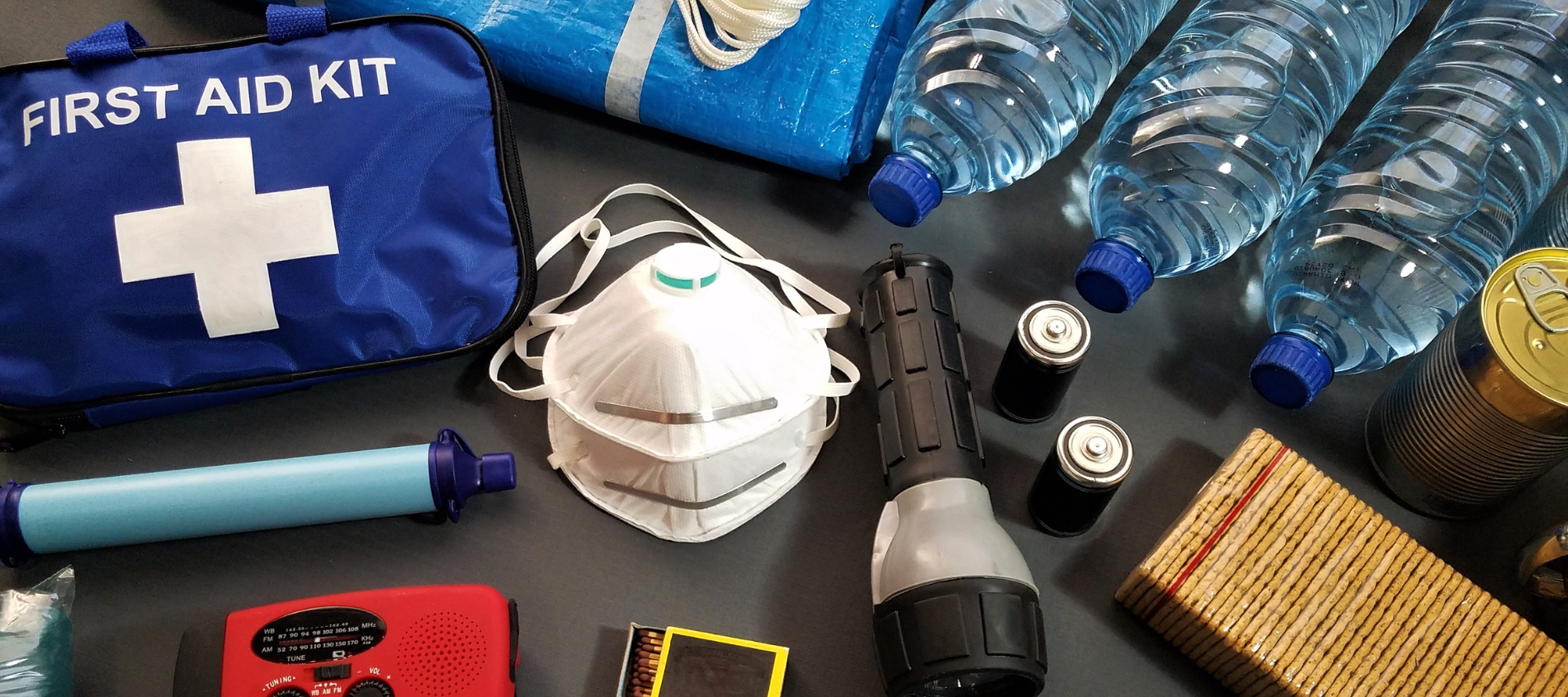 A picture of a emergency kit with water, flash light, first aid kit.