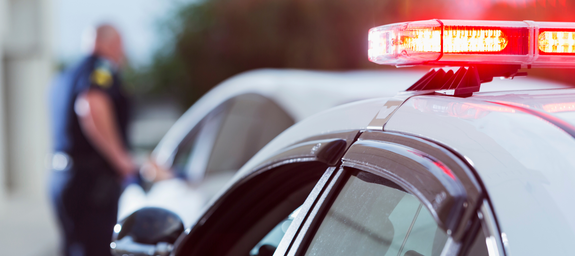 A picture of a police officer beside two cars.