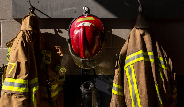 A picture of a firefighter coats and hat hanging up on the wall