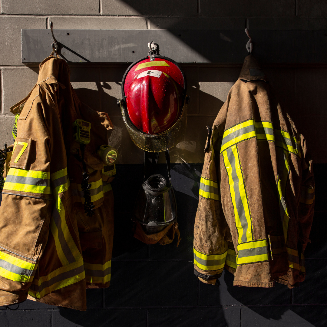 A picture of firefighter coats hanging up against a wall